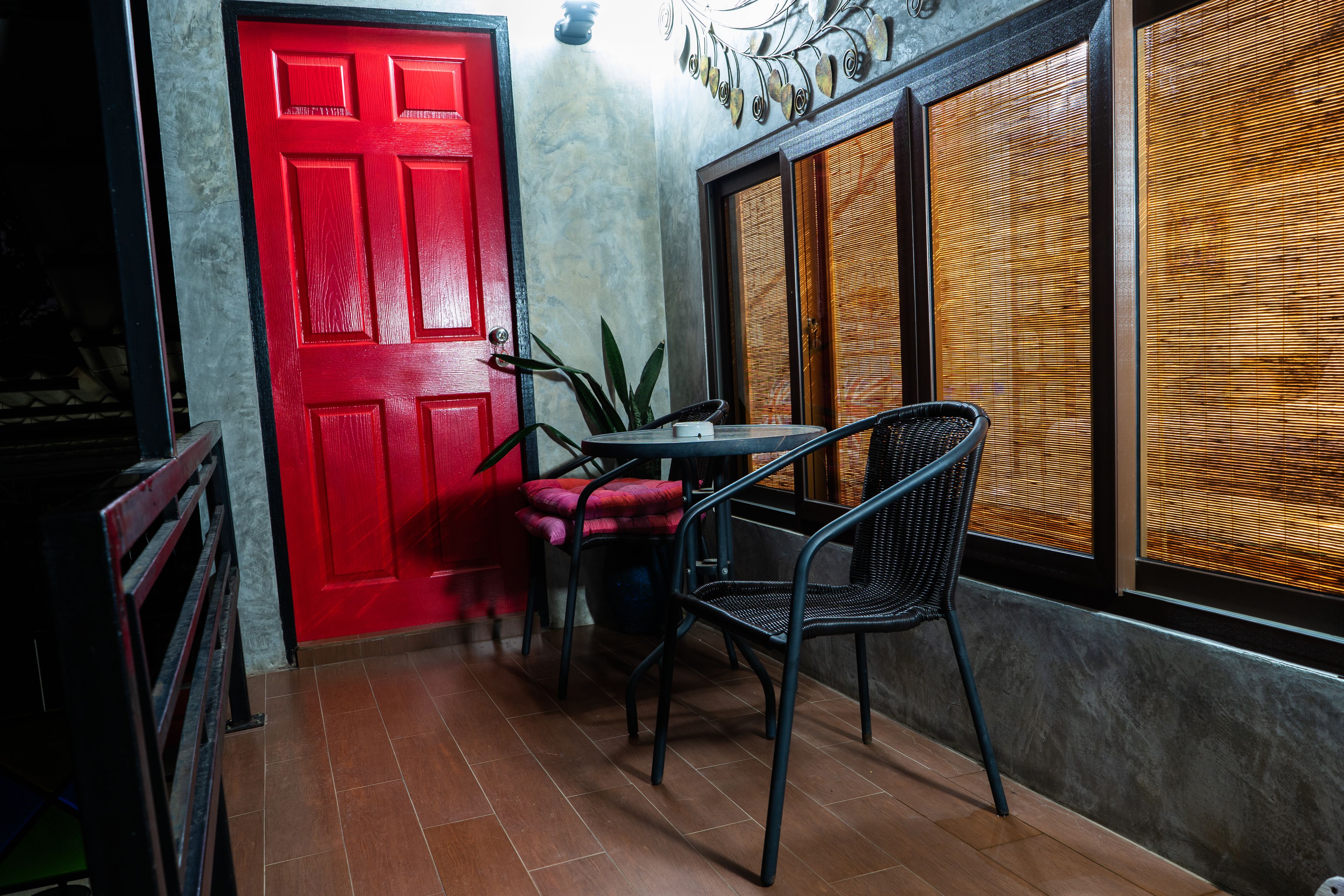 A room with a red door, a small table, two chairs, and a potted plant.