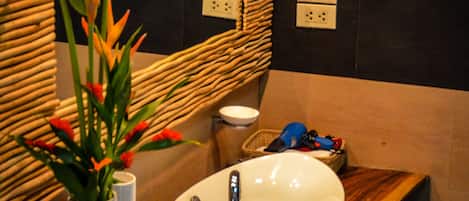Un baño con tocador de madera, un lavabo blanco y un espejo.