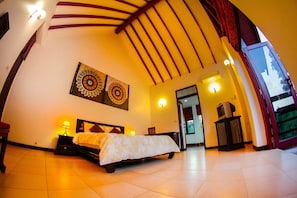A spacious bedroom with a bed, two wall-mounted lamps, and a large window.