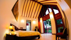 Een slaapkamer met een bed, nachtkastje en televisie. Er staat een stoel en een deur naar een buitenruimte.