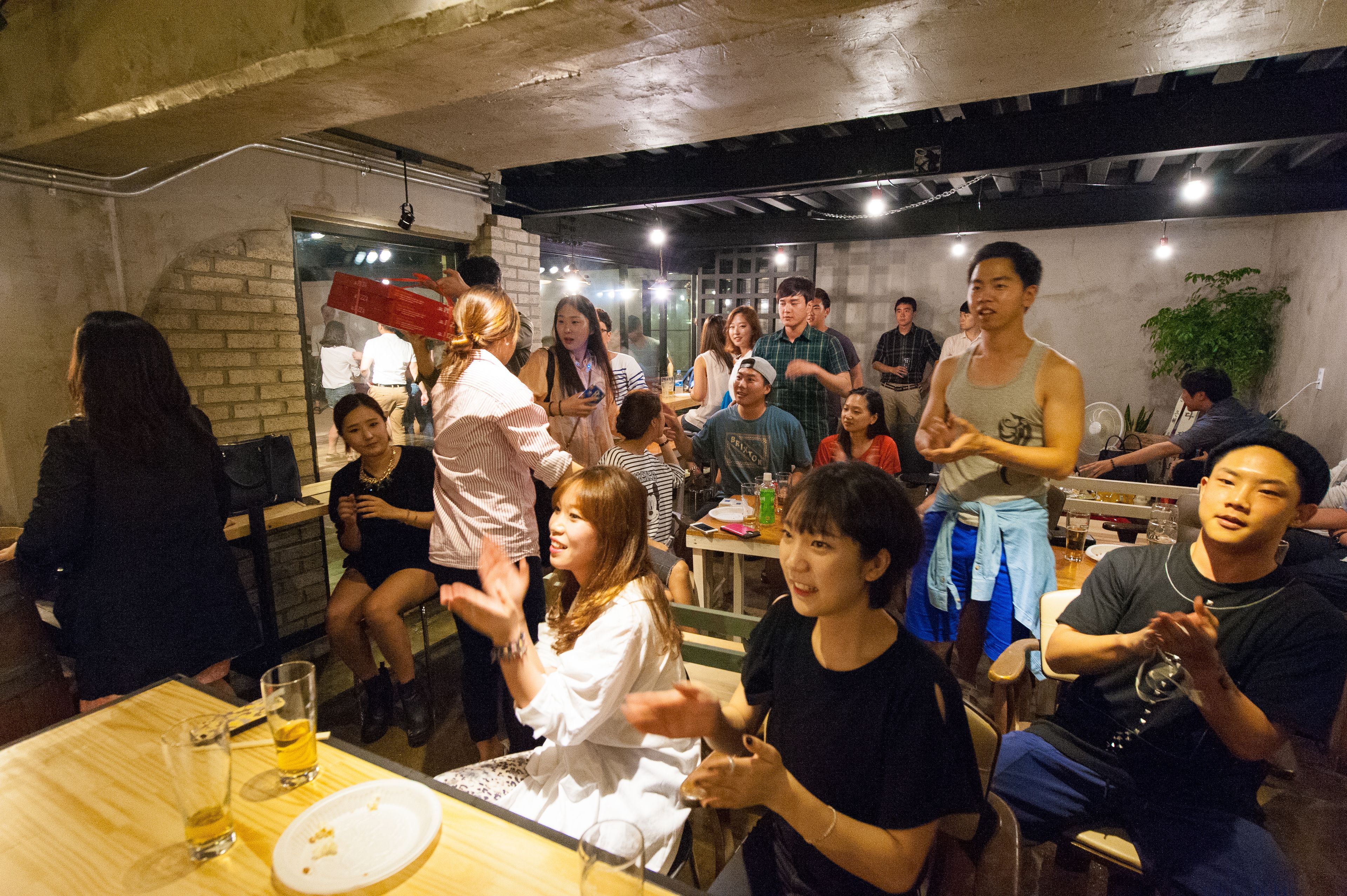 A group of people seated at a restaurant with a brick wall and industrial-style ceiling.