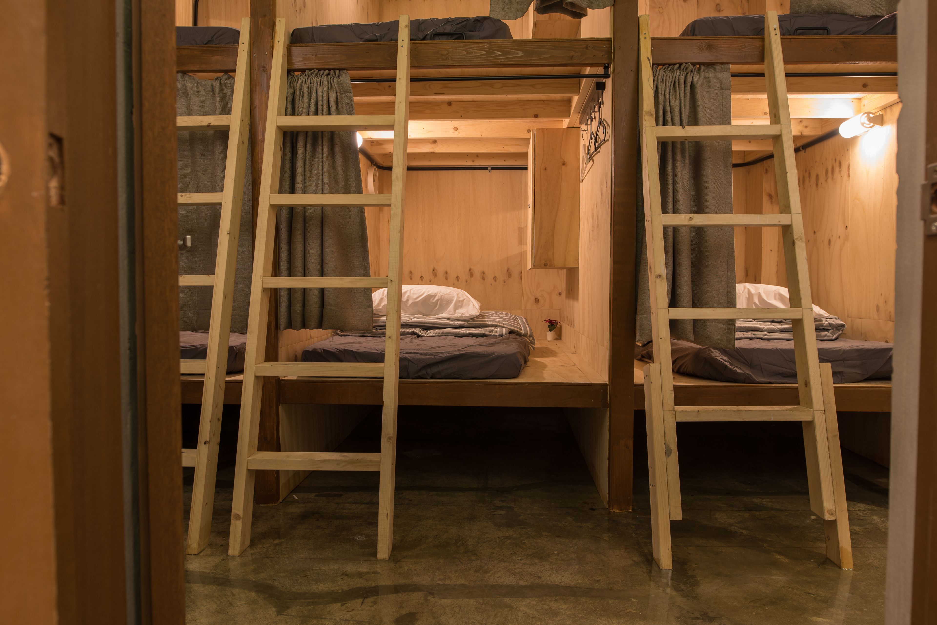 A bunk bed room with wooden ladders and curtains.