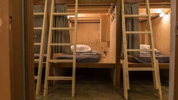 A bunk bed room with wooden ladders and curtains.