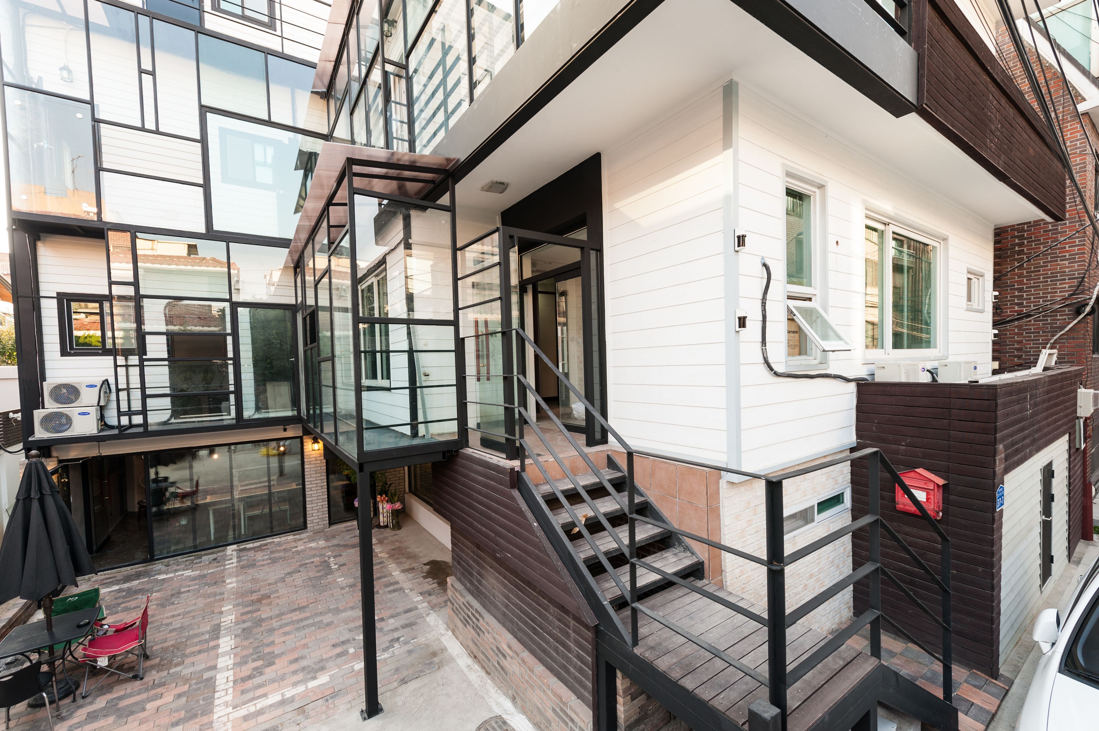 A modern residential building with a staircase leading to an upper floor, a glass door entrance, and a brick exterior.