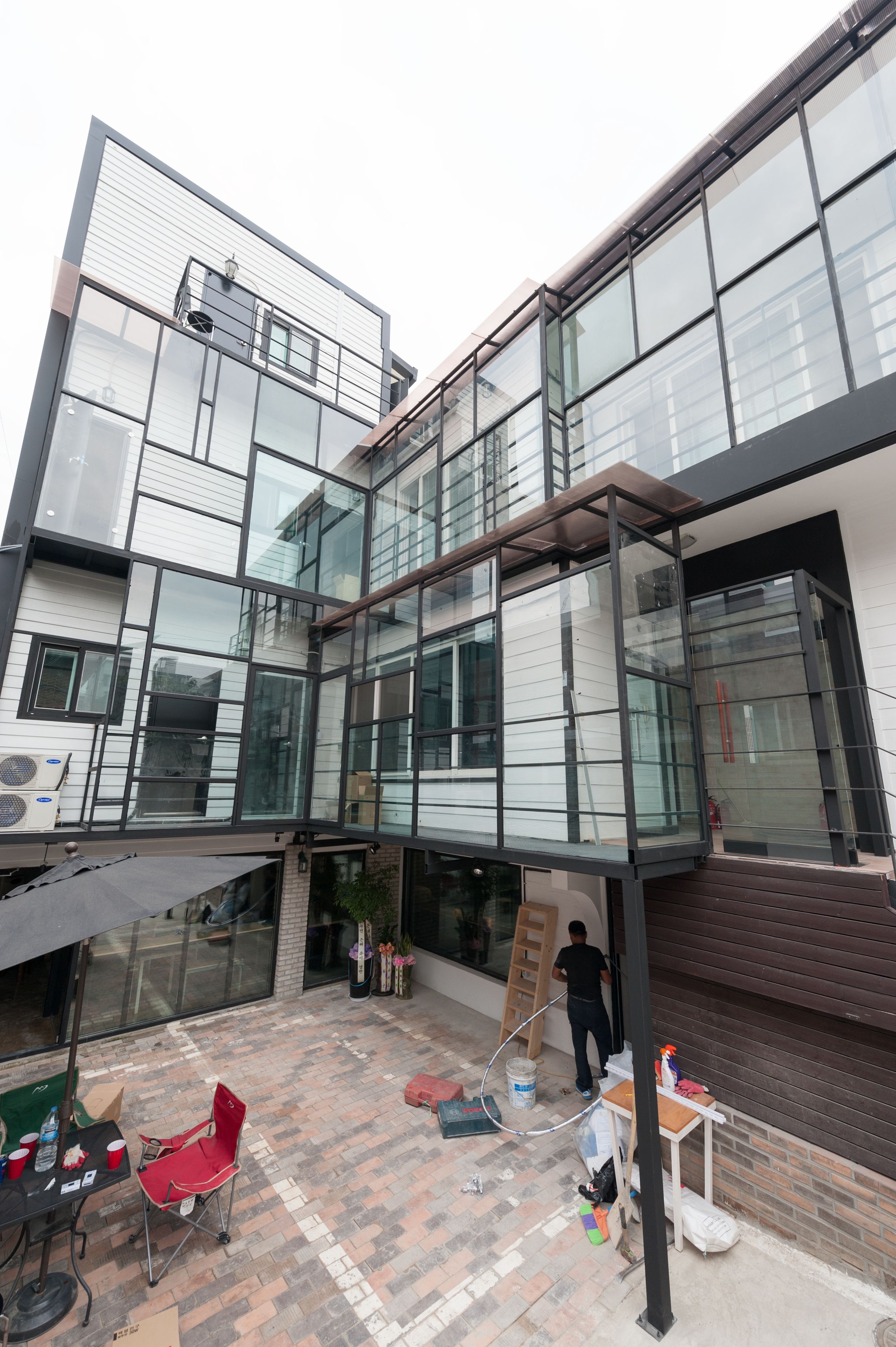 A modern building with large glass windows and a patio area with outdoor seating.