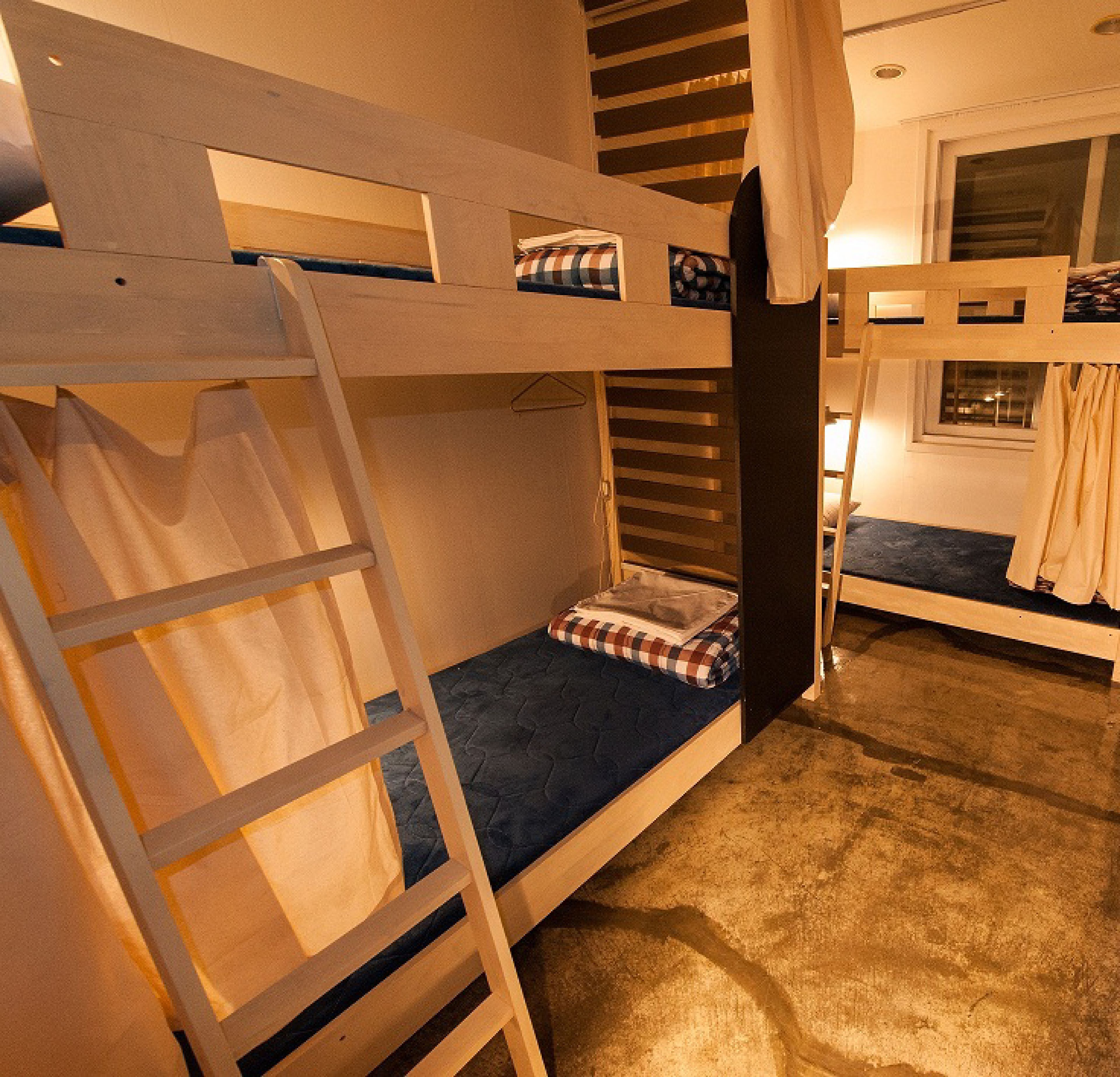 Habitación con literas, una escalera, una ventana y una cortina.