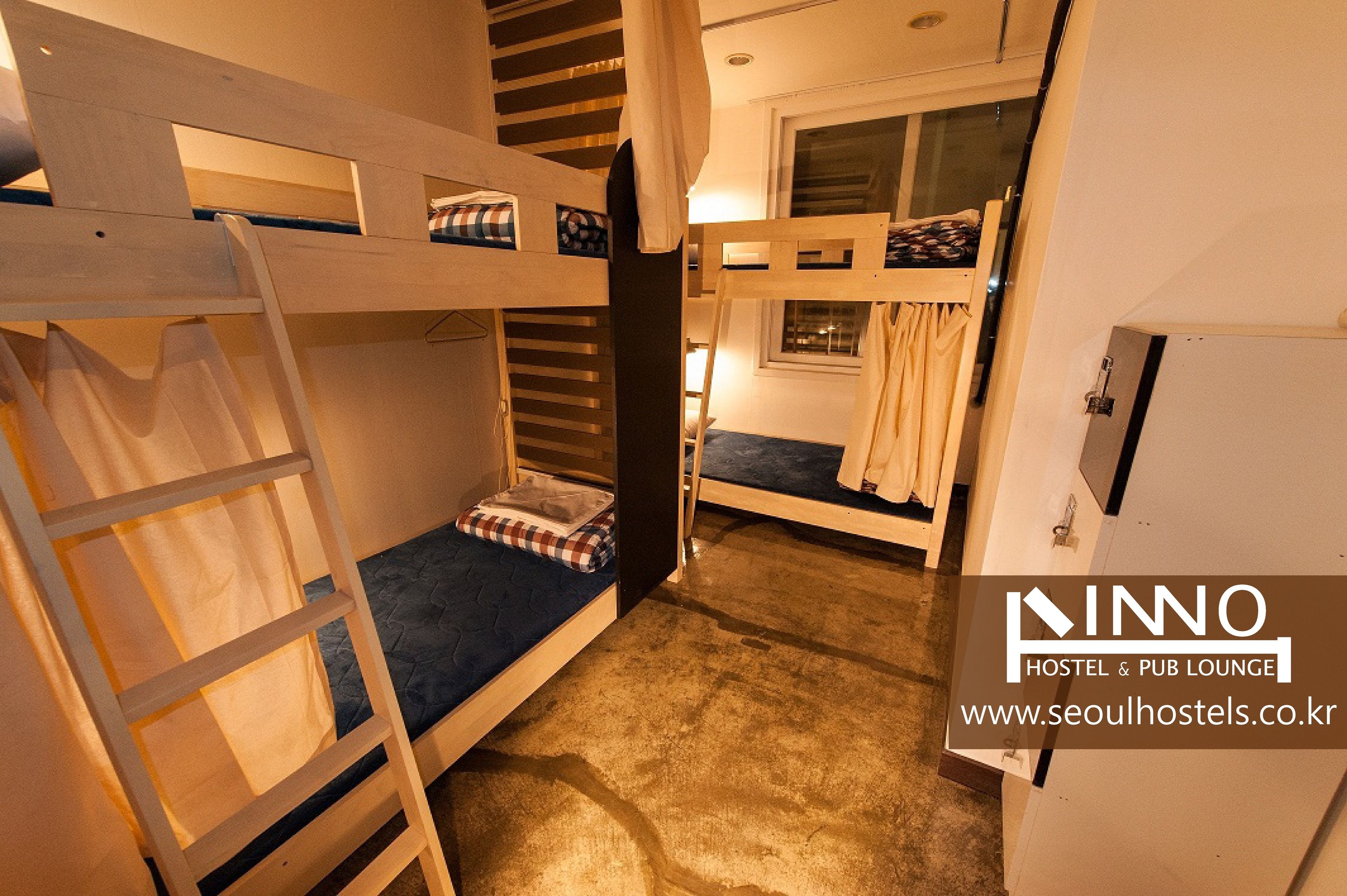 A dormitory-style room with bunk beds, a ladder, and a window.