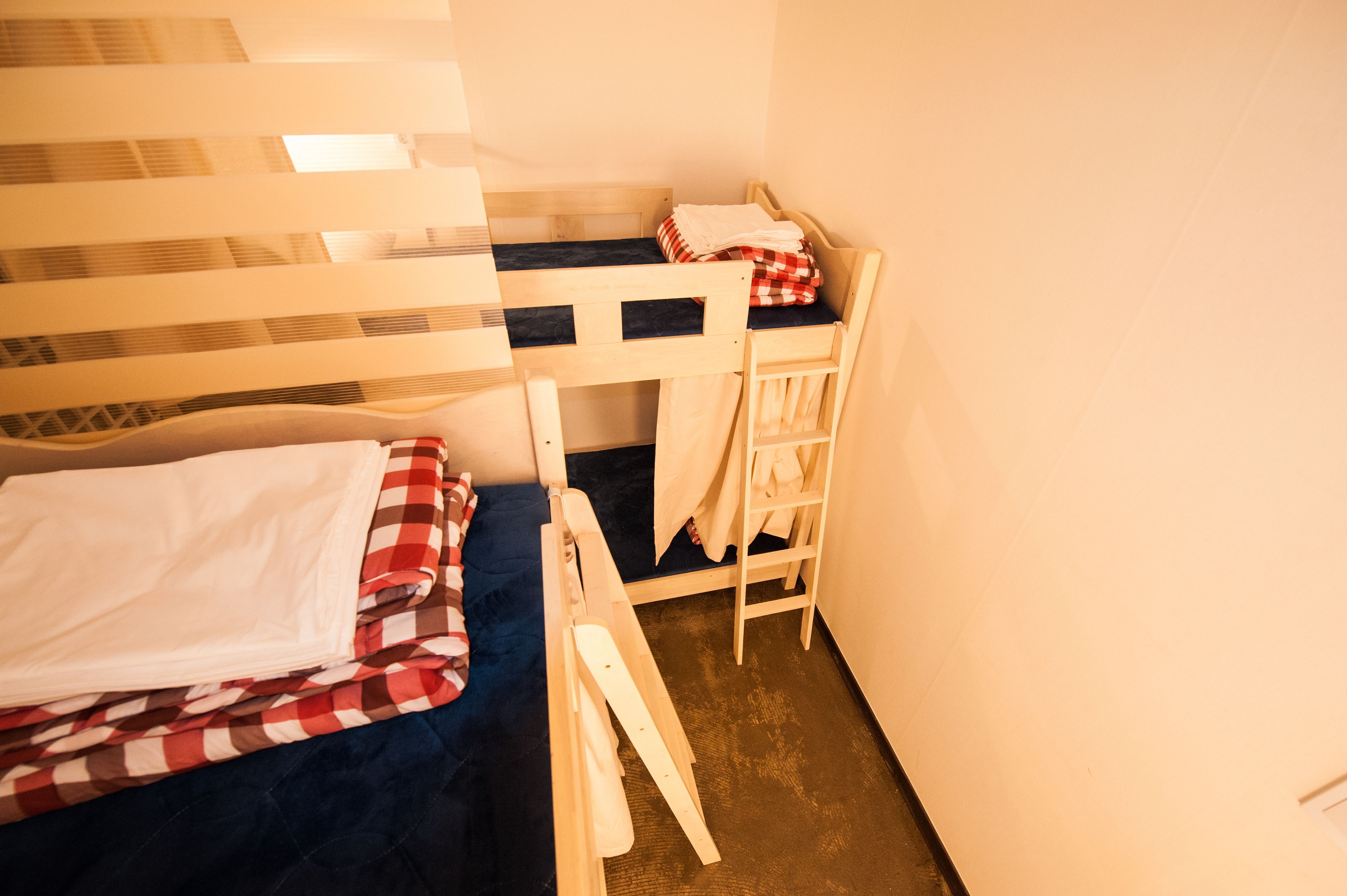 A bunk bed room with a ladder, a small desk, and a chair.