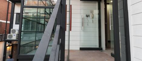A modern building entrance with glass doors, a metal staircase, and a tiled floor.