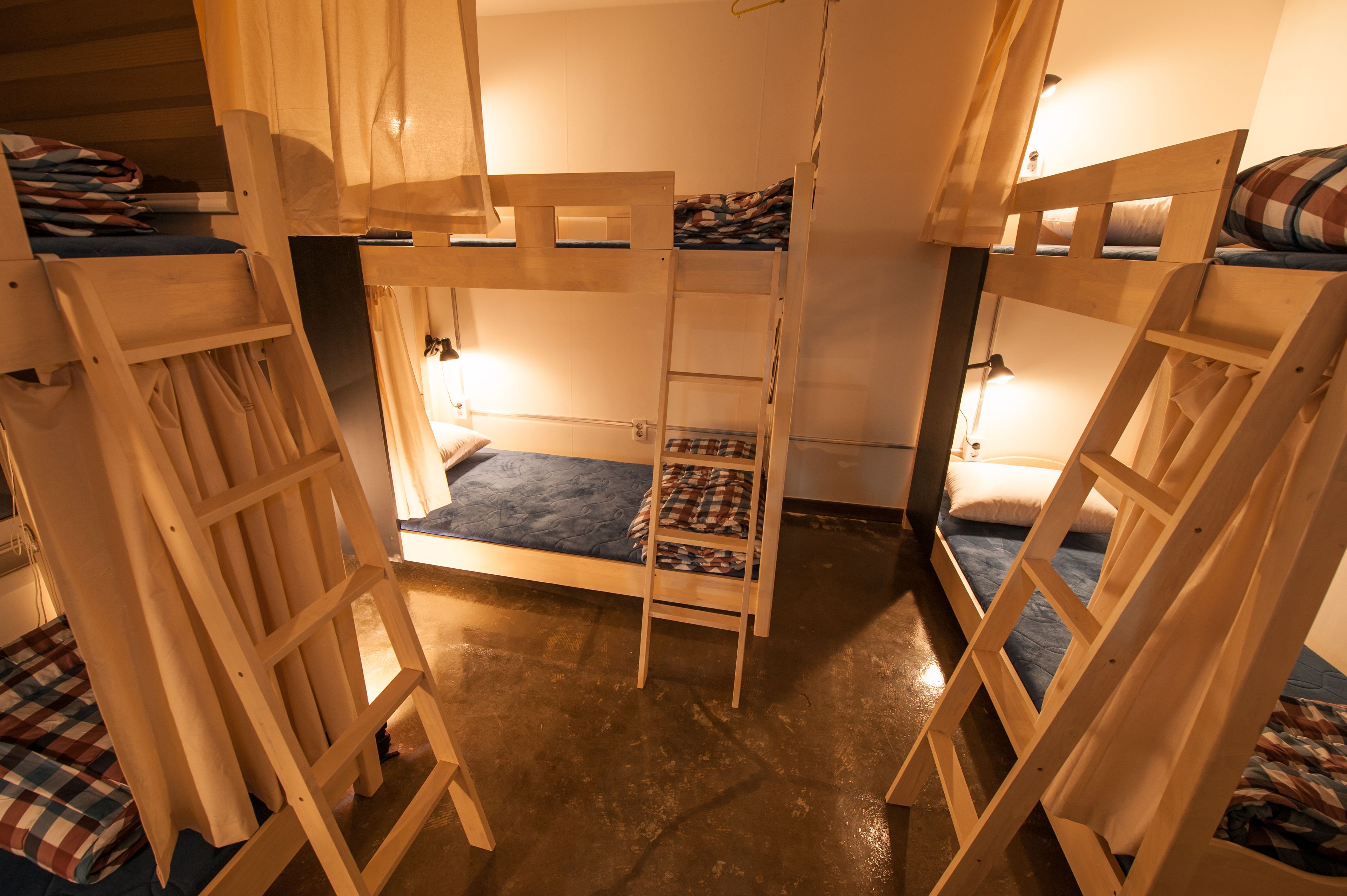 A bunk bed room with a ladder, wooden railings, and a blue mattress.