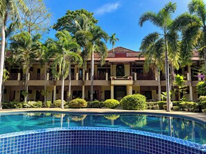 A hotel with a swimming pool, palm trees, and a multi-story building with balconies. - Rattana Guesthouse & Bungalow (Koh Samui)