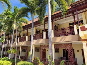 A multi-story hotel with balconies, palm trees, and a traditional architectural style. - Rattana Guesthouse & Bungalow (Koh Samui)