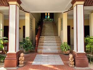 A staircase leading to a building entrance with columns and potted plants. - Rattana Guesthouse & Bungalow (Koh Samui)