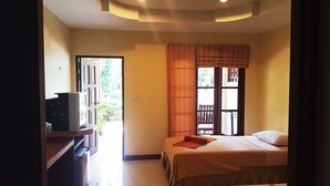 A bedroom with a bed, a TV, and a window with curtains. - Rattana Guesthouse & Bungalow (Koh Samui)