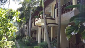 A multi-story hotel with balconies, palm trees, and a garden pathway. - Rattana Guesthouse & Bungalow (Koh Samui)