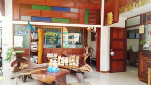 A ticket counter with wooden furniture and a large display window. - Rattana Guesthouse & Bungalow (Koh Samui)