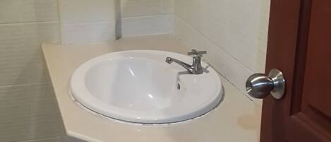 Un baño con un lavabo blanco, un espejo y una puerta.