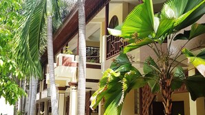 A building with multiple balconies, surrounded by lush greenery and palm trees. - Rattana Guesthouse & Bungalow (Koh Samui)