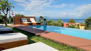 Una piscina con sillas de descanso y vista al mar.