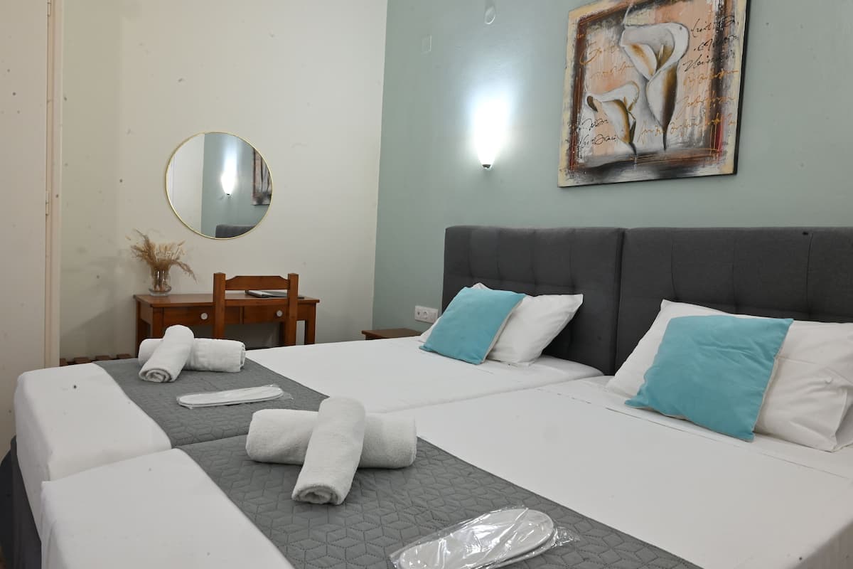 Habitación de hotel con una cama grande, dos almohadas, una mesita de noche, un espejo y un cuadro en la pared.