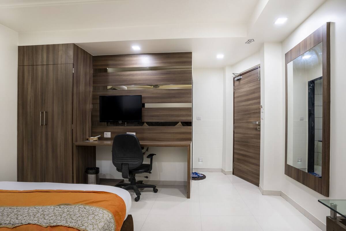 Ein Schlafzimmer mit Bett, Schreibtisch mit Stuhl, Fernseher und Kleiderschrank.