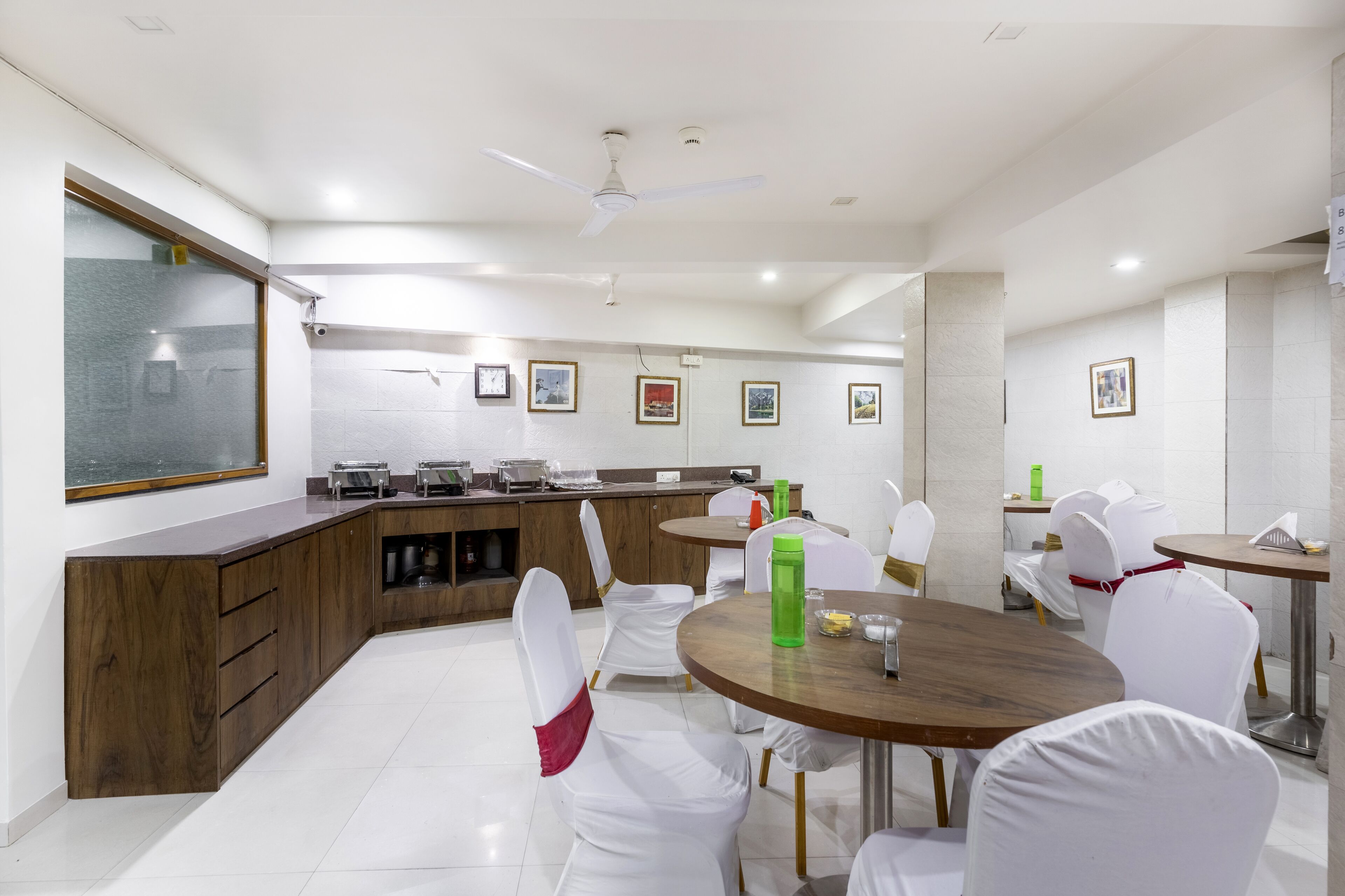 A modern kitchen with white chairs, a wooden counter, and a ceiling fan.
