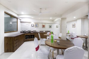 A modern kitchen with white chairs, a wooden counter, and a ceiling fan.