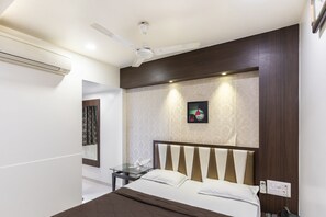 A modern hotel room with a bed, a nightstand, a ceiling fan, and a wall-mounted artwork.