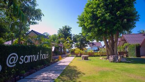 Ein Weg führt zu einem Gebäude, an dem ein Schild mit der Aufschrift „@ samui house“ angebracht ist.