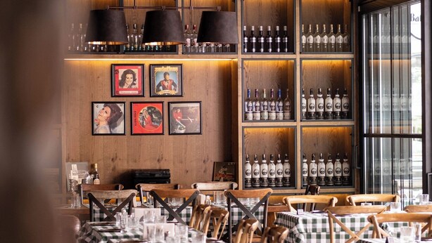 Ein Restaurant mit karierten Tischdecken, Holzwänden und hängenden Pendelleuchten.