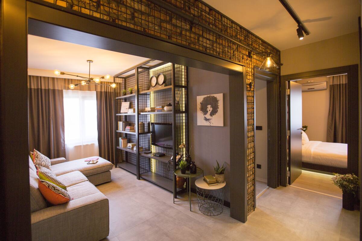 A modern living room with a sofa, a small side table, and a bookshelf.