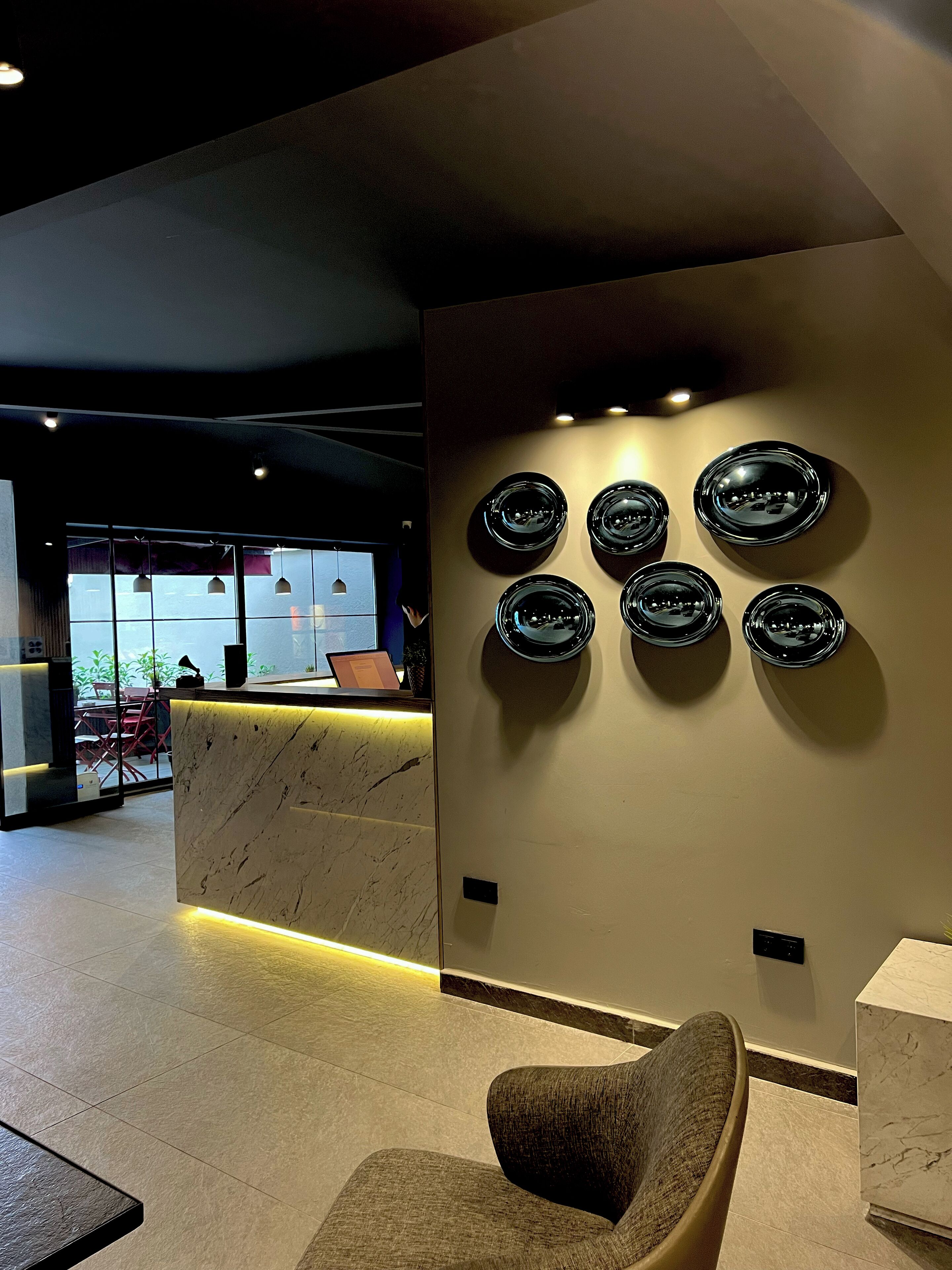 A modern reception area with a marble counter, a seating area with a chair, and wall-mounted decorative plates.