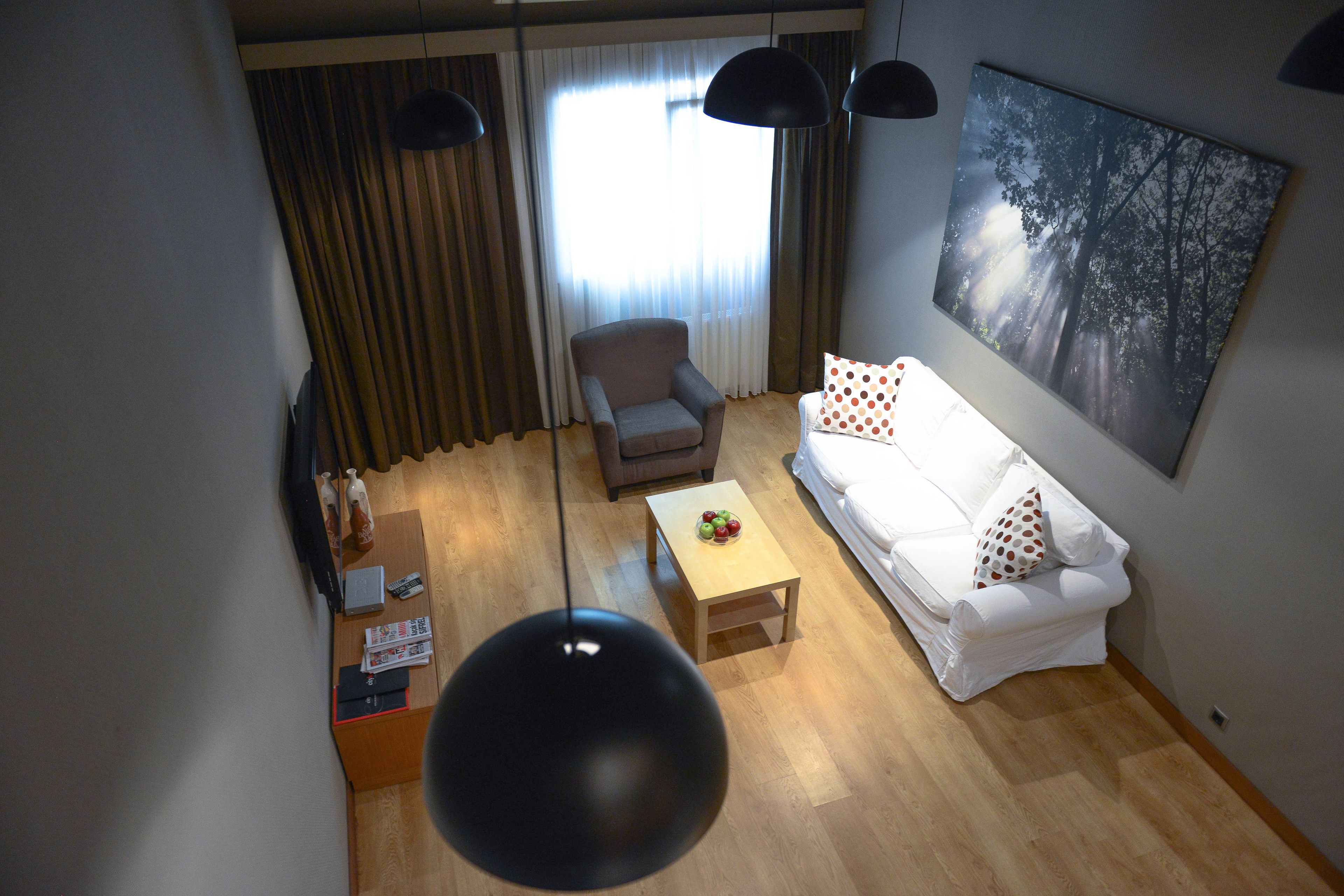 A living room with a white sofa, a grey armchair, a wooden coffee table, and a painting on the wall.