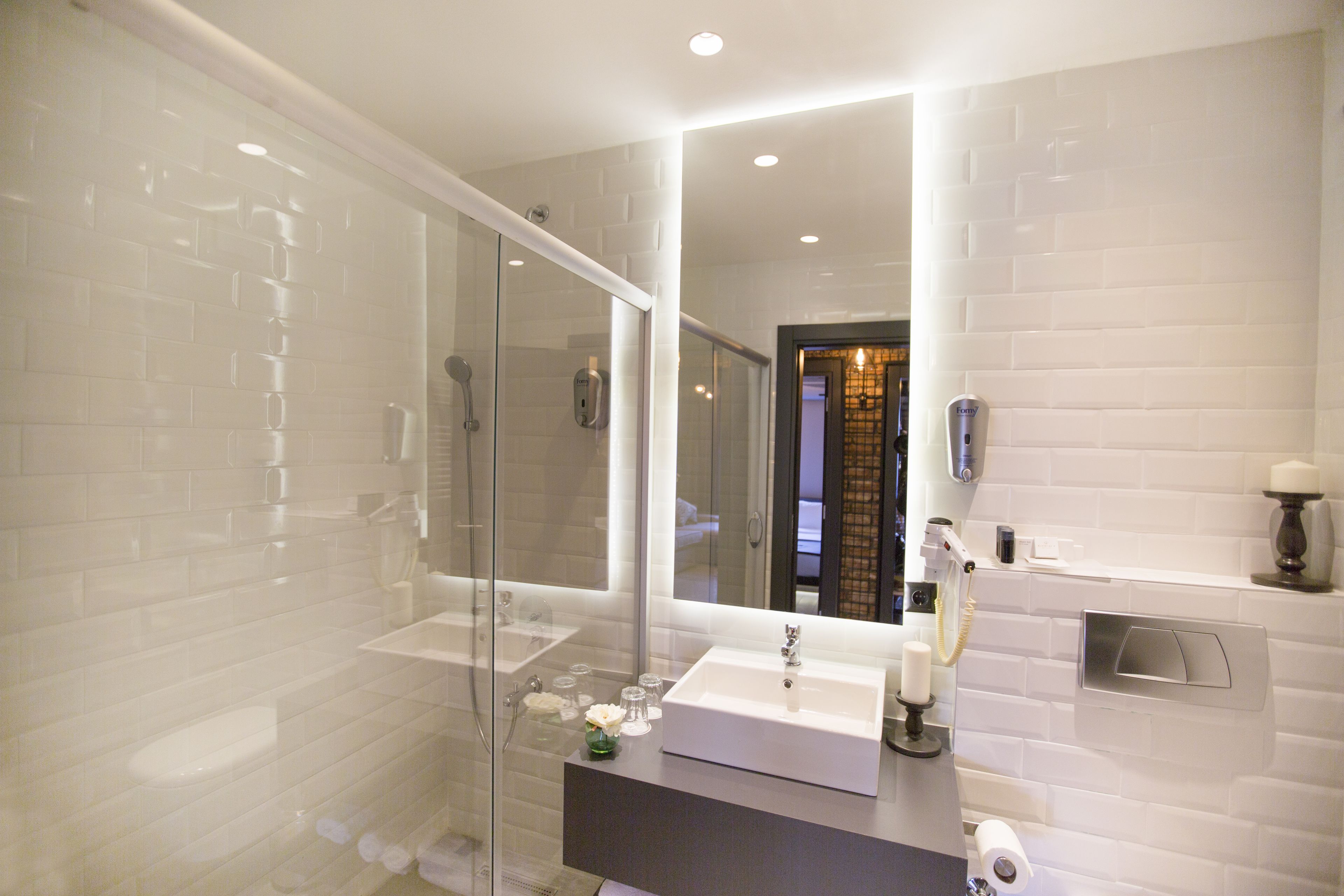 A modern bathroom with a glass-enclosed shower, a white sink, and a large mirror.