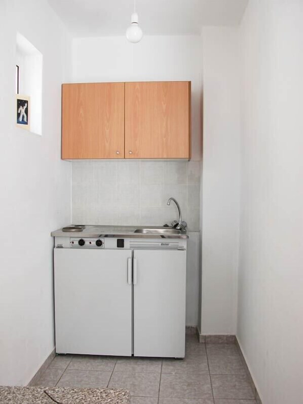 A compact kitchen with a built-in stove, sink, and wooden cabinets. - Tasmania Village (Agios Nikolaos)