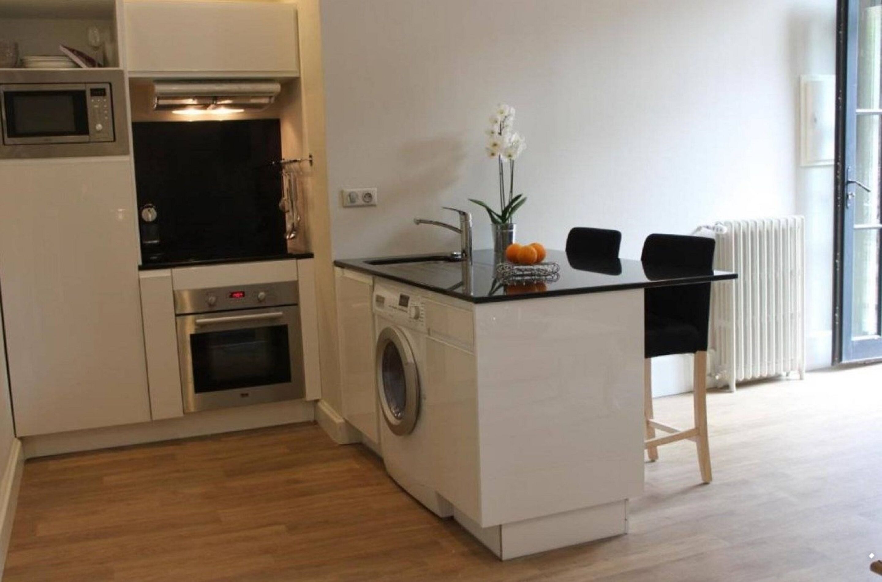 A compact kitchenette with a microwave, oven, and washing machine.