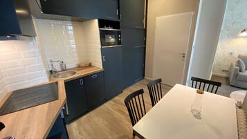 Una cocina moderna con armarios oscuros, una encimera blanca y una mesa de comedor de madera con sillas.