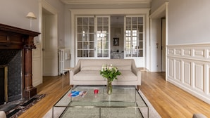 Un salon avec un canapé beige, une table basse en verre et une cheminée.
