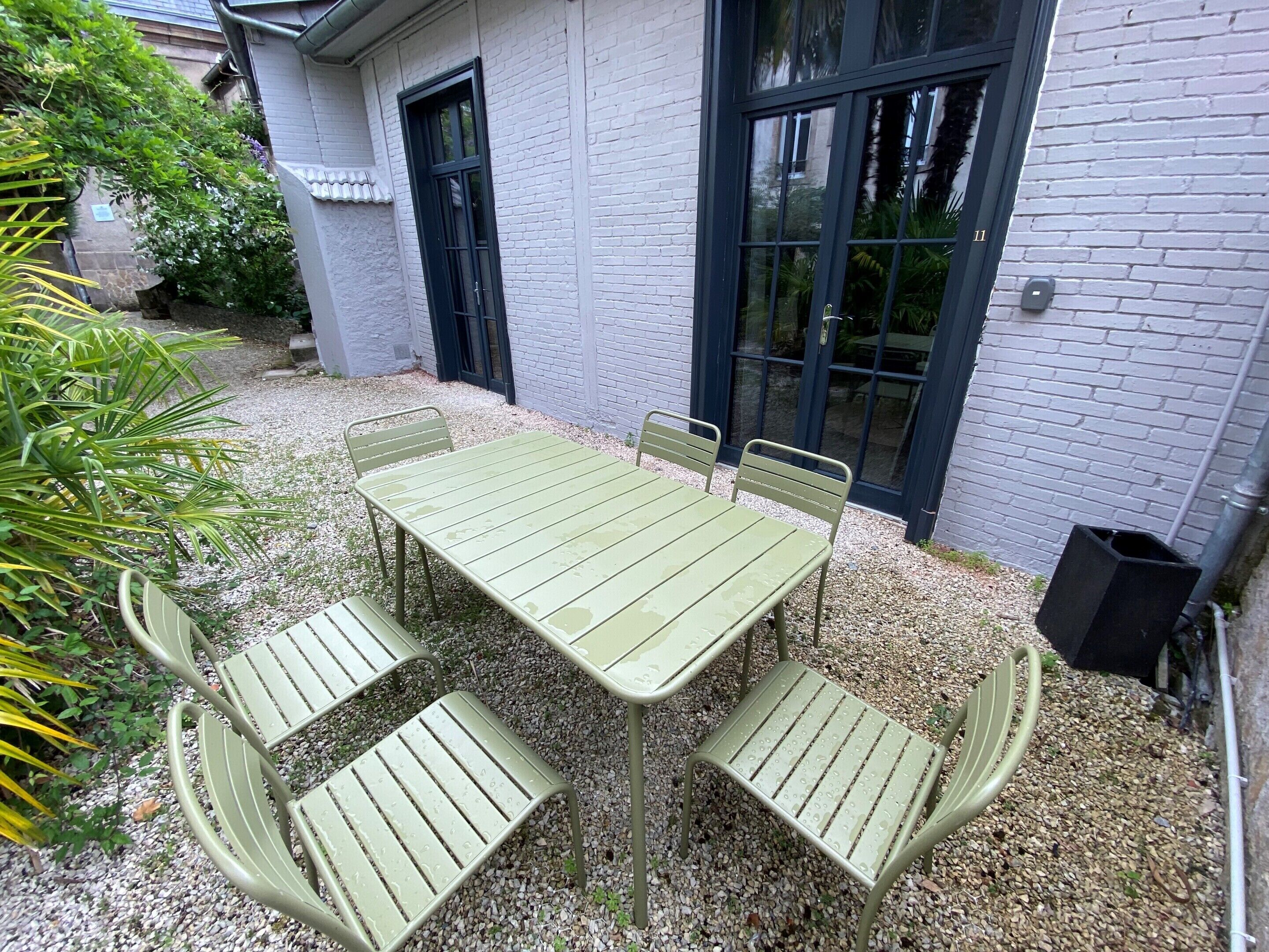 En terrasse med bord og stole, omgivet af grus og planter.