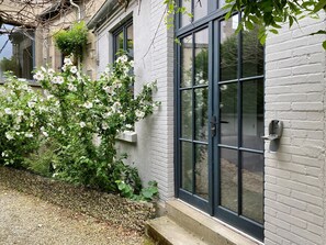 A building with a white brick exterior, a large window with a dark frame, and a door with a handle. - La Villa Beaupeyrat (Limoges)