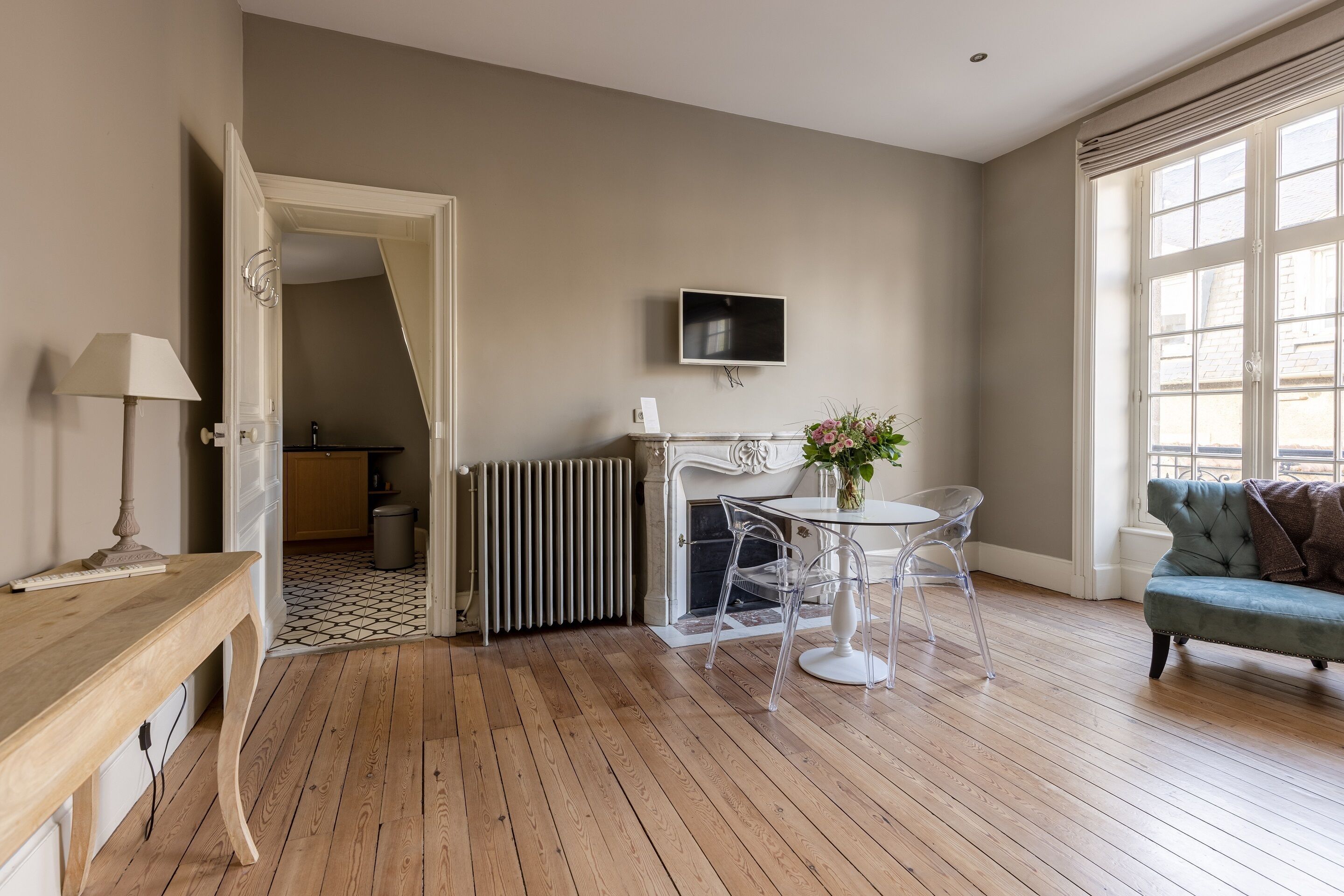 Un salon spacieux doté d’un plancher en bois, d’un canapé, d’un téléviseur fixé au mur et offrant une vue dégagée sur l’extérieur grâce à de grandes fenêtres.