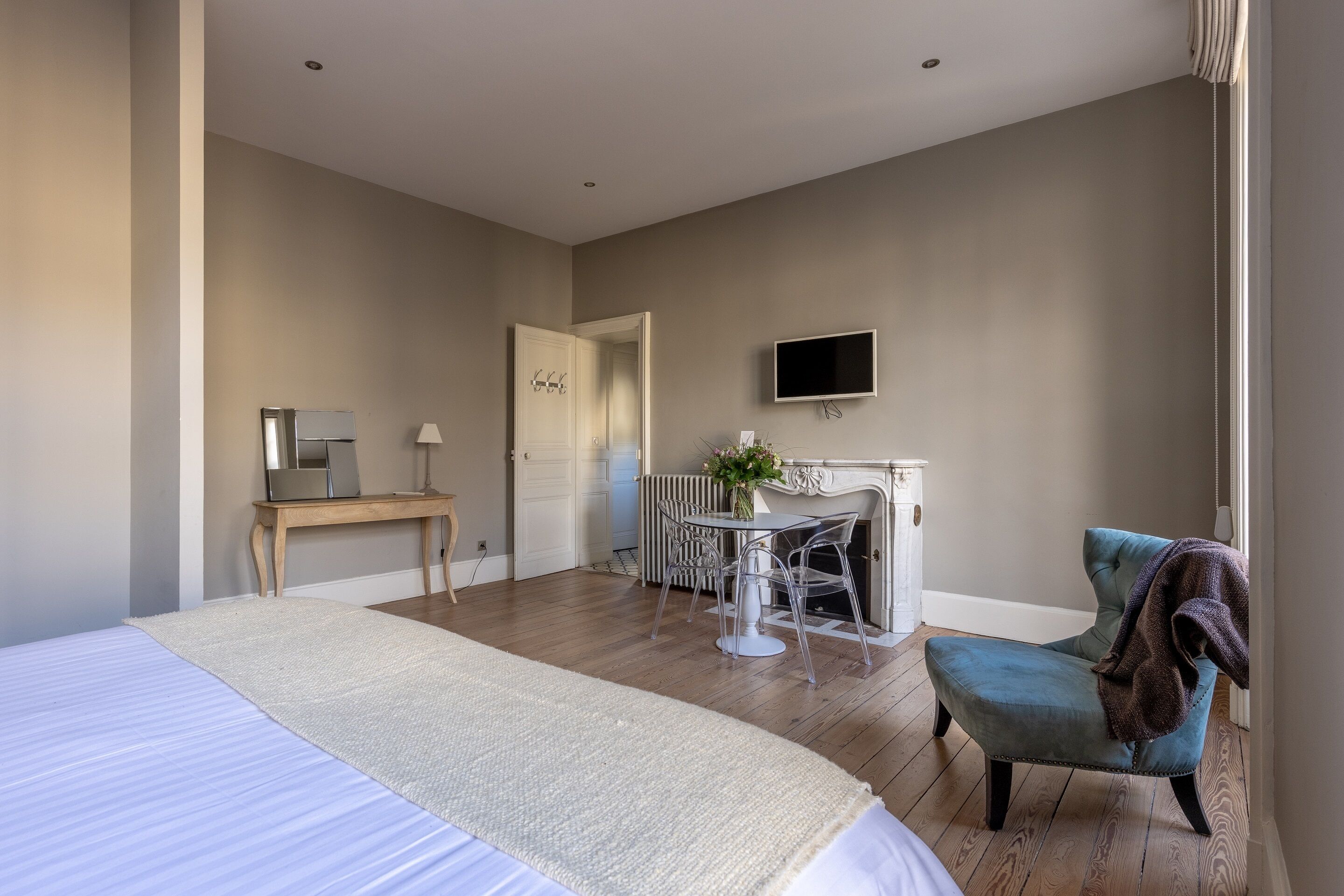 A bedroom with a bed, a desk, a chair, a fireplace, and a television.