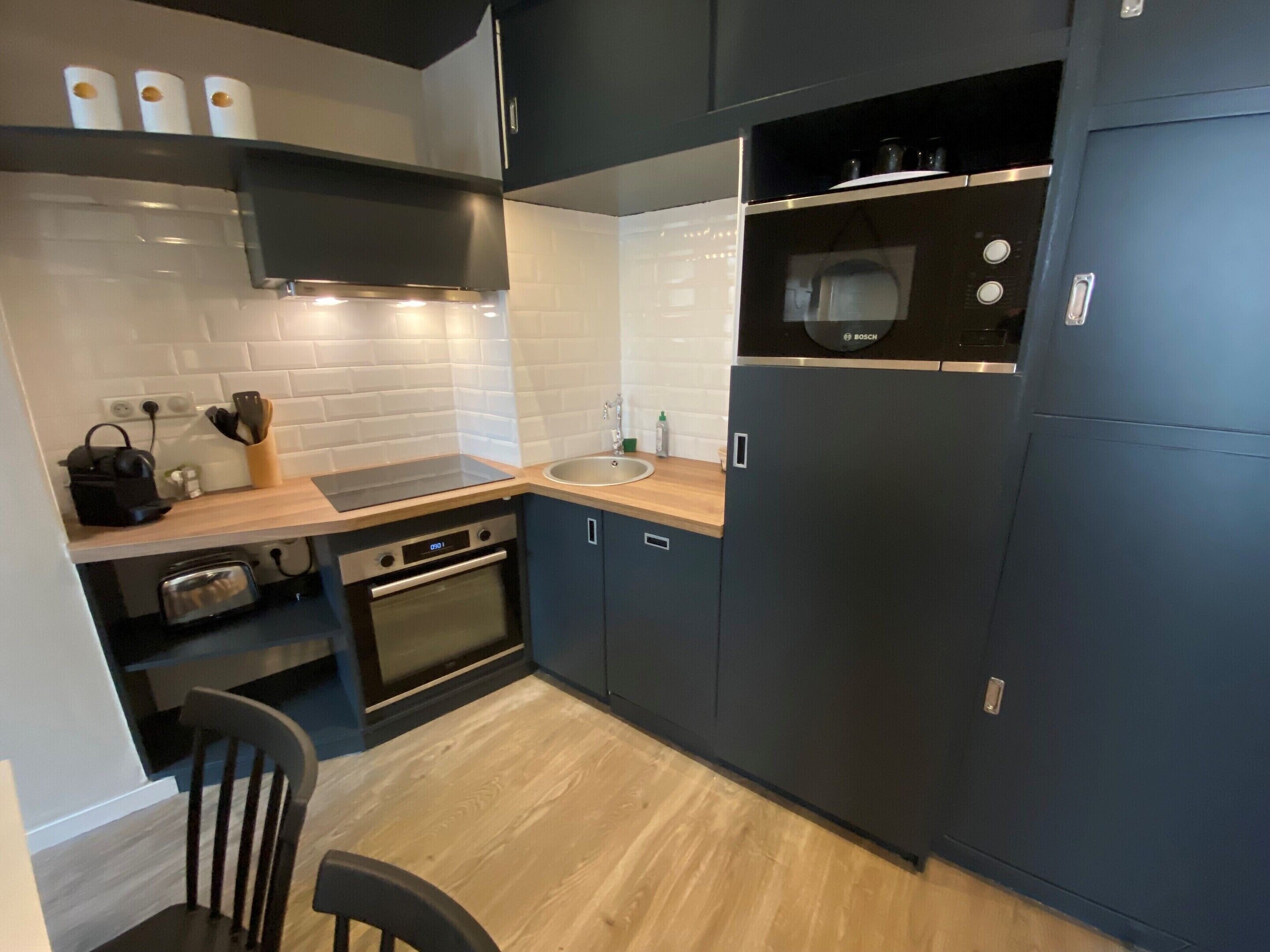 Una cocina moderna con horno empotrado, un microondas Bosch y un lavamanos.