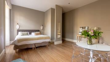 A bedroom with a bed, bedside tables, a round dining table, and a vase with flowers.