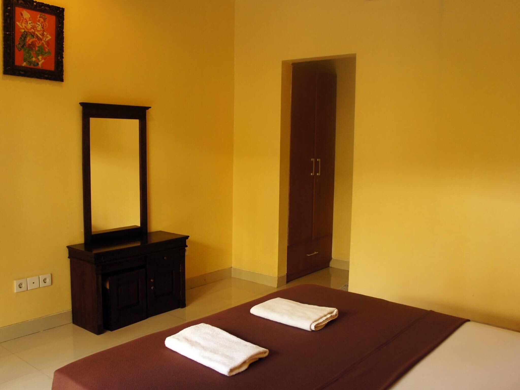 A hotel room with a bed, a dresser, a mirror, and a wardrobe.