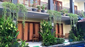 A hotel with multiple balconies, indoor plants, and a swimming pool. - Waringin Home Stay (Kuta)