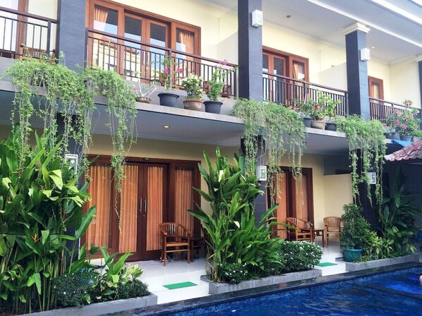 A hotel with multiple balconies, indoor plants, and a swimming pool. - Waringin Home Stay (Kuta)