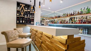 A bar area with a wooden counter, leather chairs, and a variety of liquor bottles. - Dave Hotel Yerevan (Yerevan)