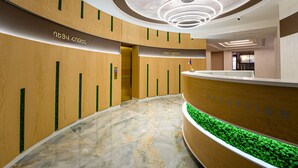 A modern hotel reception area with a wooden reception desk, a marble floor, and a circular ceiling light fixture. - Dave Hotel Yerevan (Yerevan)