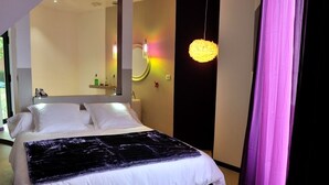 Een moderne slaapkamer met een groot bed, een spiegel en een bijzondere hanglamp.